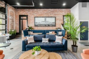 A cozy and modern lounge area within a graduation party venue, featuring plush blue sofas, chic decor, and exposed brick accents, creating an inviting atmosphere for guests celebrating a graduation event.