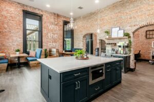 A modern and stylish interior of a graduation event space with exposed brick walls and contemporary furnishings, featuring a central kitchen island that serves as a versatile venue for a graduation party