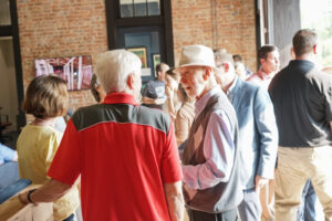 Guests conversing and enjoying a gathering inside a spacious venue with exposed brick walls, well-suited for hosting a graduation party or similar celebration events