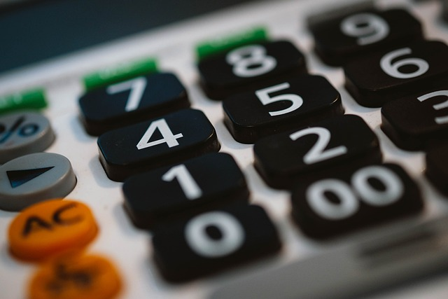 This image captures a close-up of a calculator, focusing on the keypad which features prominently numbered buttons in black with green for the enter key, an orange clear button, and white for the rest of the function keys. The perspective provides a glimpse into the daily tools used in business, finance, or educational settings, where calculations are an integral part of the activities.