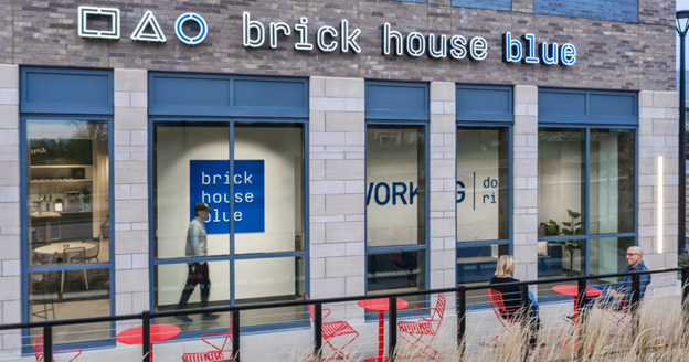 Exterior view of brick house blue coworking and meeting space, featuring modern design elements with people engaging in conversation, indicative of the collaborative and social environment it offers for remote workers and businesses.